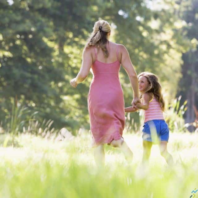 Woman and young girl running outdoors holding hands